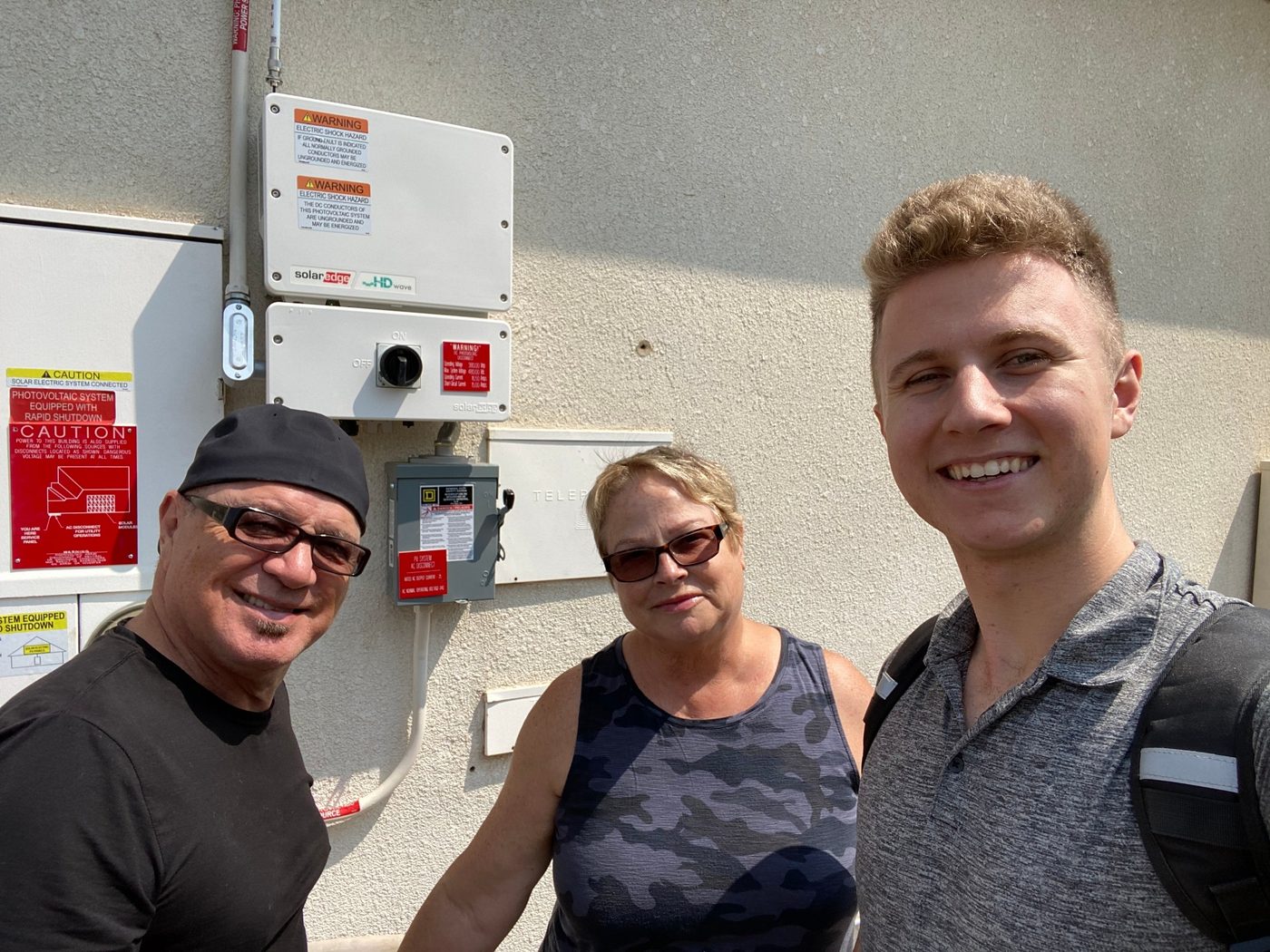 Conner Leeb with homeowners beside their new solar equipment